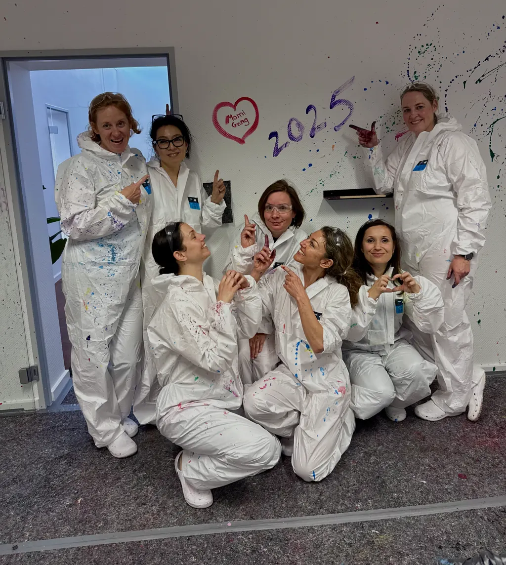 Freundinnen in Overalls vor einer Wand mit gemaltem Herz und der Zahl 2025
