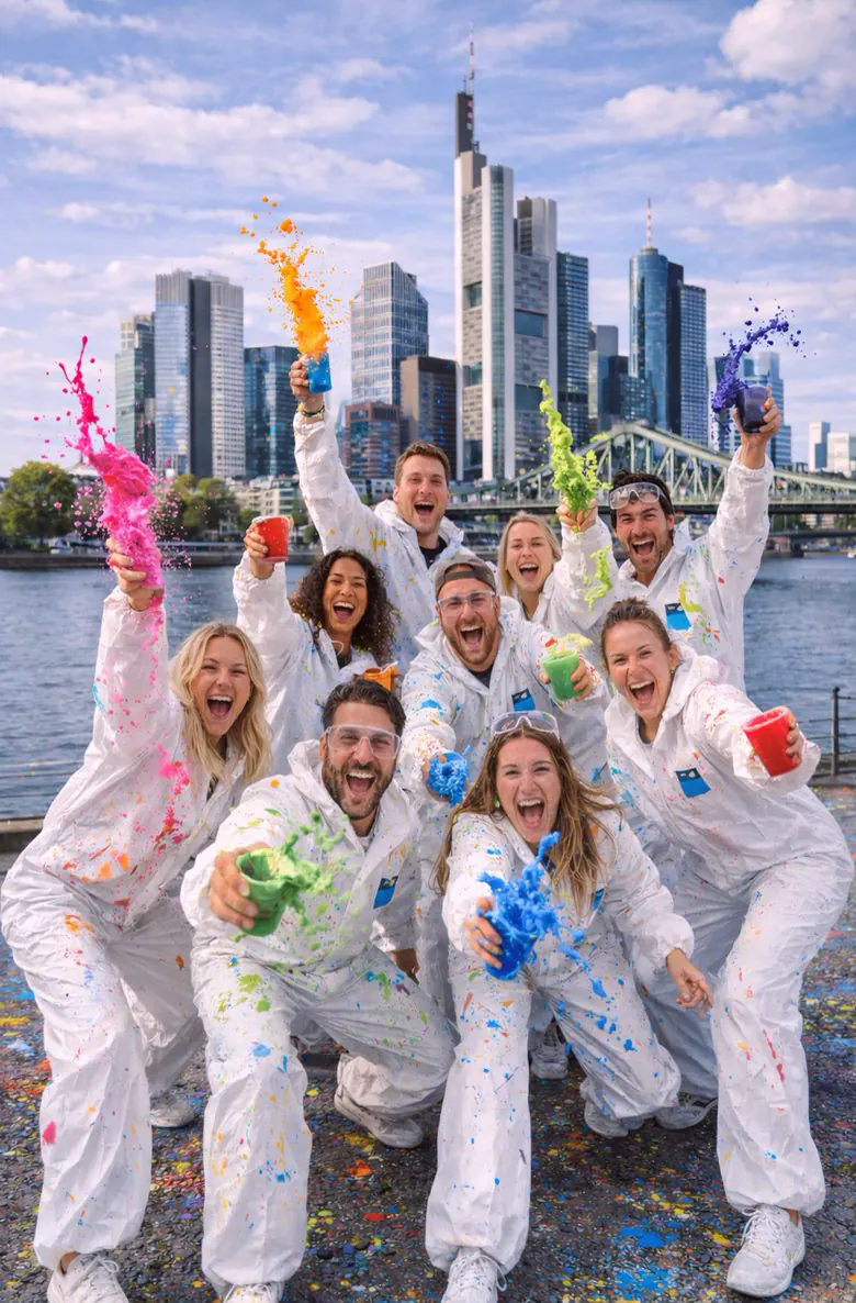 Gruppe in weißen Overalls mit fliegender Farbe vor der Frankfurter Skyline